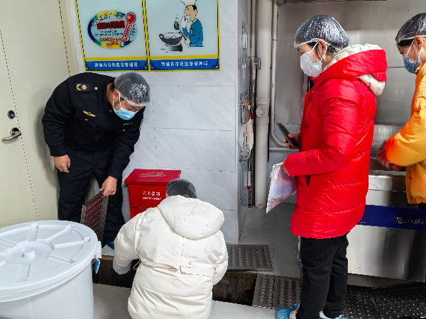 执法人员检查食堂排水设施.jpg