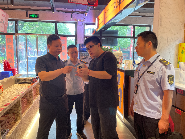 赖永兴带队在南雄市雄州街道张崇会火锅店查验肉制品电子检测报告(陈小芳摄).jpg